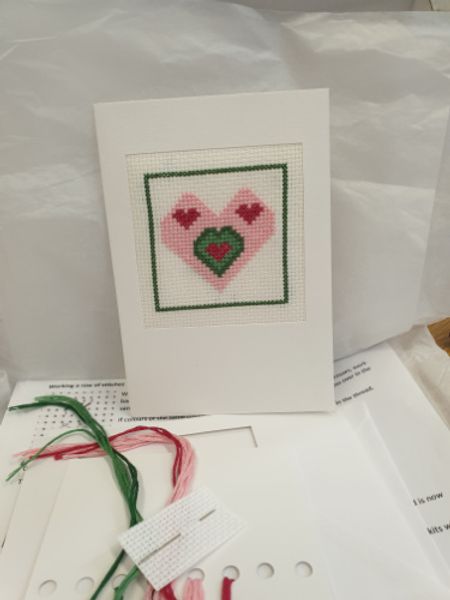 Picture shows contents of the box, everything you need to create a cross stitched heart motif with cross stitch frame