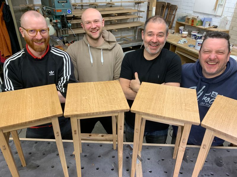 Four tired but delighted students show off their tables, with the beautiful quartersawn oak tabletops a particular feature.