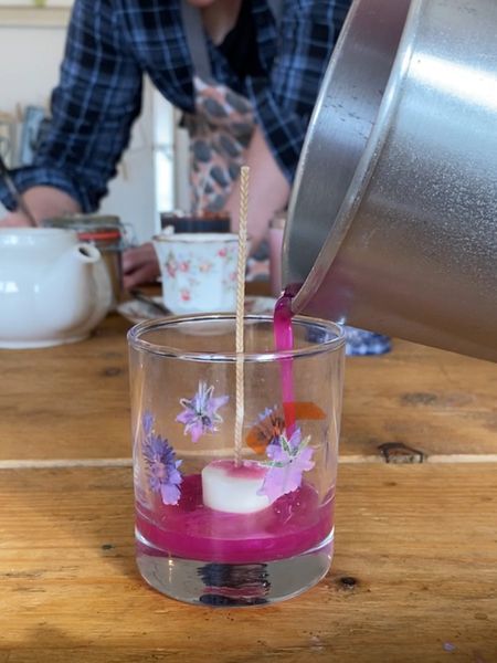 Pouring a bright pink candle from a metal jug