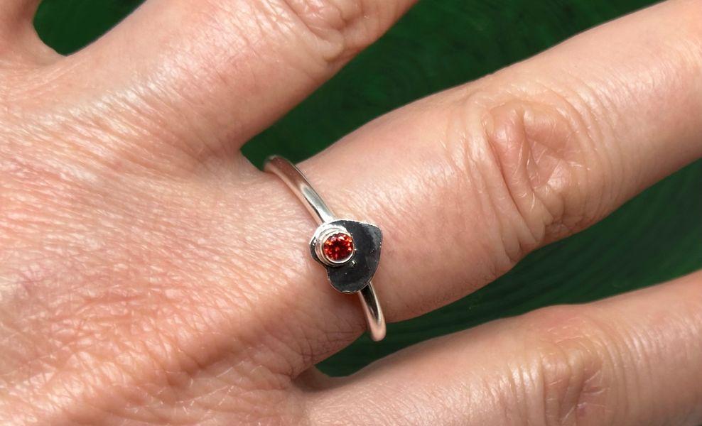 sterling silver adjustable heart wrap ring with red stone on finger