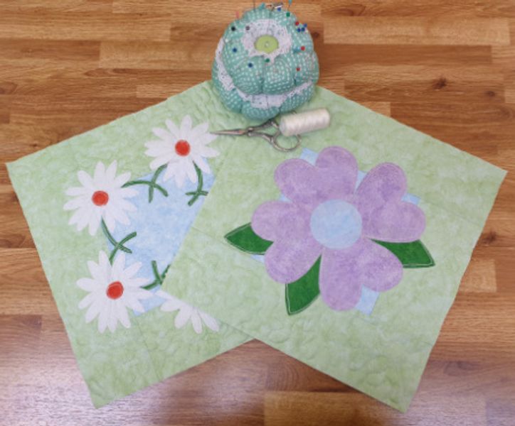 Two appliqué designs on table.  The Flower block will be demonstrated in class