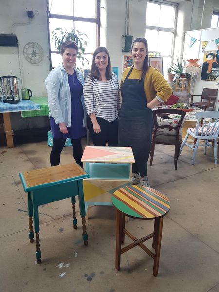 Three friends showing off their wonderful creations on the furniture upcycling workshop