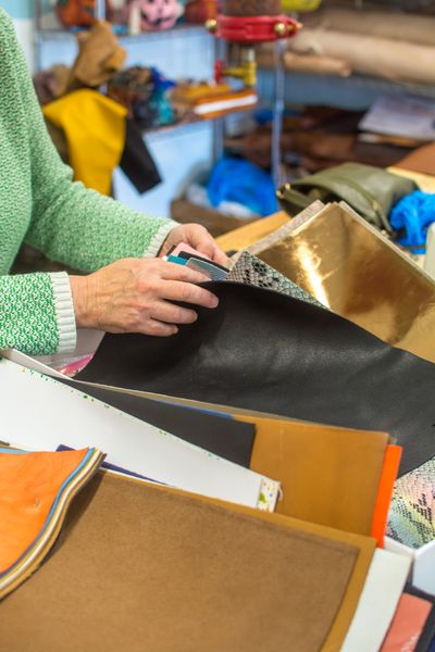 Student looking through leather pieces at craft workshop