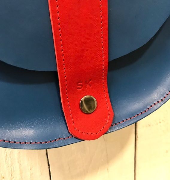 Close up of leather saddle bag showing popper clasp and embossed initials