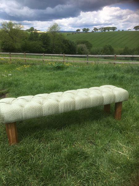 A deep buttoned footstool for the end of a double bed