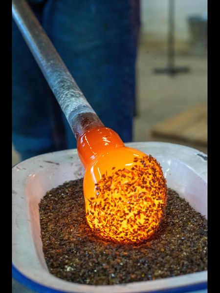 Rolling molten glass into glass colour chips at blowfish glass blowing