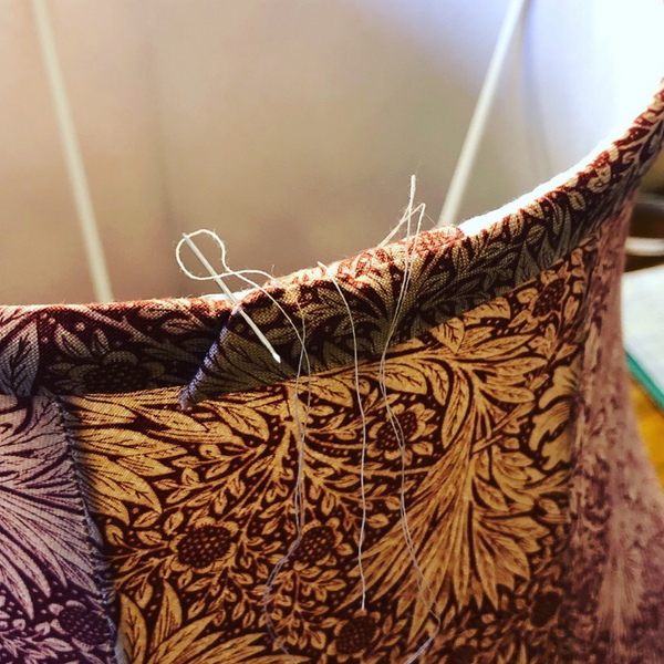 Hand stitching bias onto a traditional handmade tailored lampshade in Morris