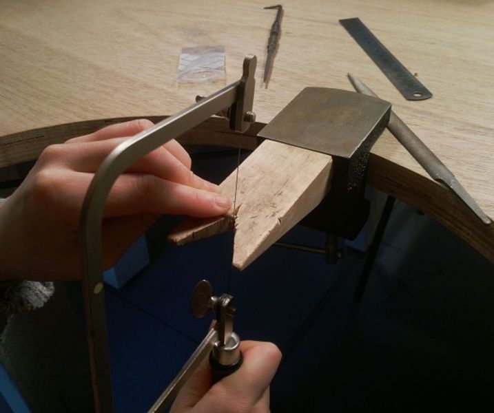 Sawing through silver to create a silver ring at a jewellery making workshop, wales