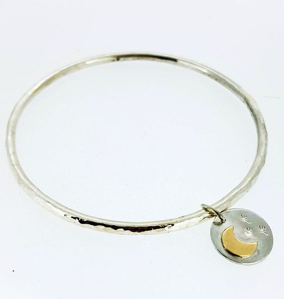 A bangle made at a silver jewellery workshop with a charm and gold moon