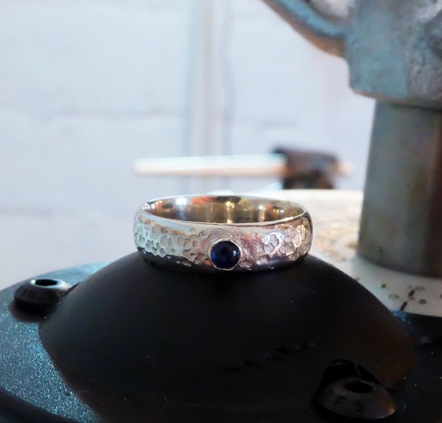 Textured silver ring with small sapphire cabochon, made by a student