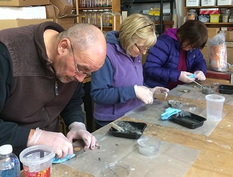 Eyes down, no talking!!! Just kidding, participants concentrating as they learn to grout their test piece mosaics.