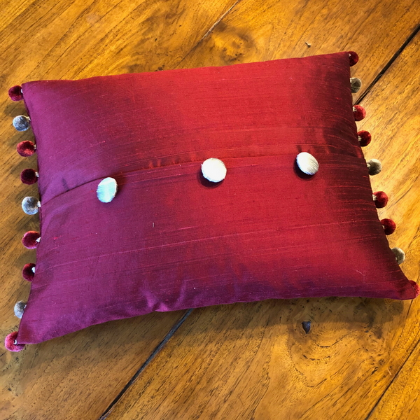 Scatter cushion in hues of red and grey with pom pom and handmade buttons