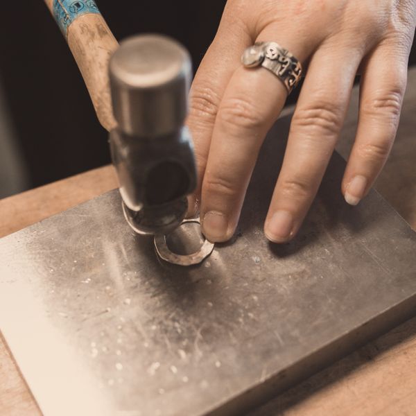 Hammering silver shapes before making them into earrings