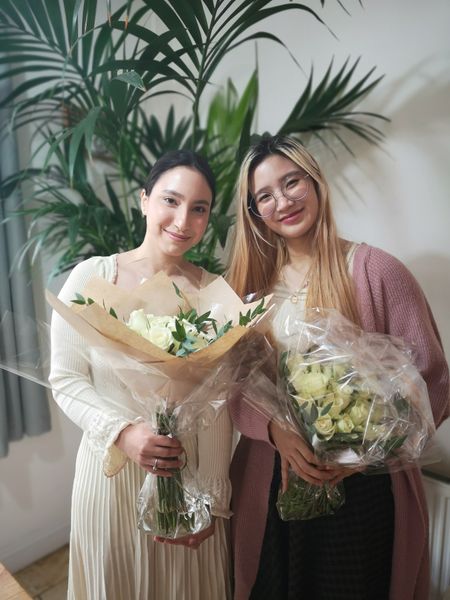 two friends smiling holing a bouqet with roses 