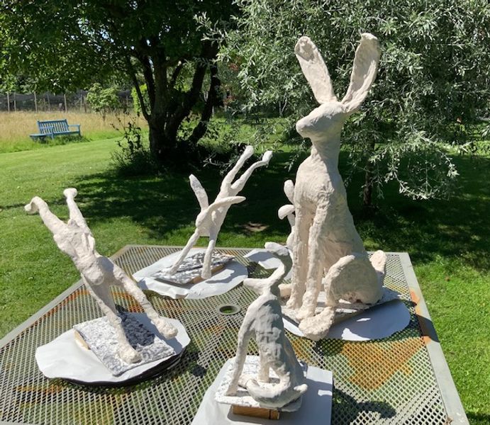 Large hare towering over small hares in plaster stage