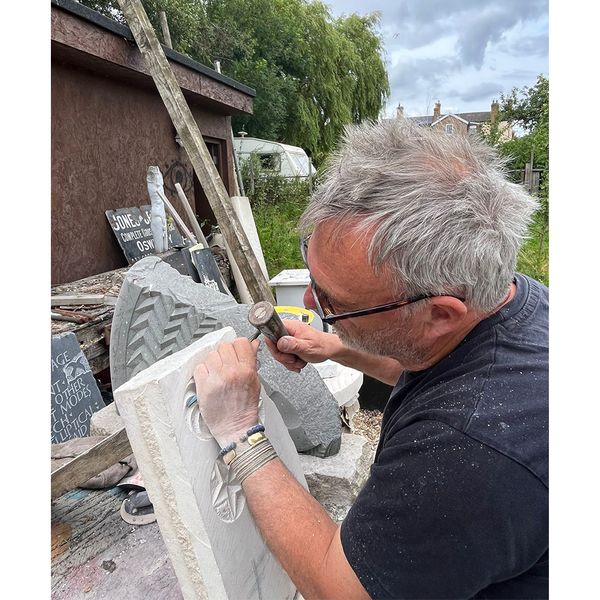 Stone mason carving out geometric patterns
