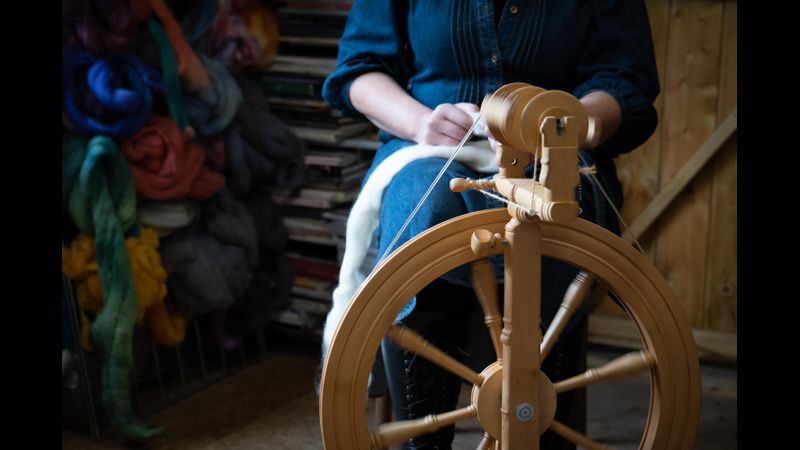 Woman sits at a Kromski Sonata Spinning Wheel