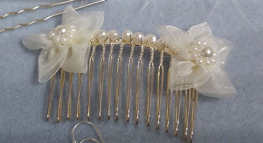 Hair comb of gold pearl and ribbon with two flowers of ribbon at either end.