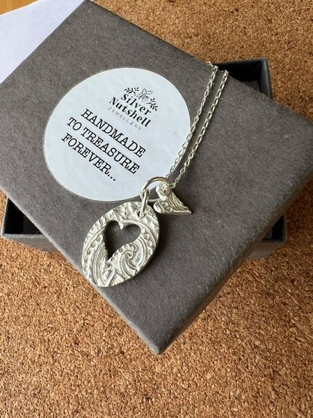 Oval embossed silver pendant with heart cutout