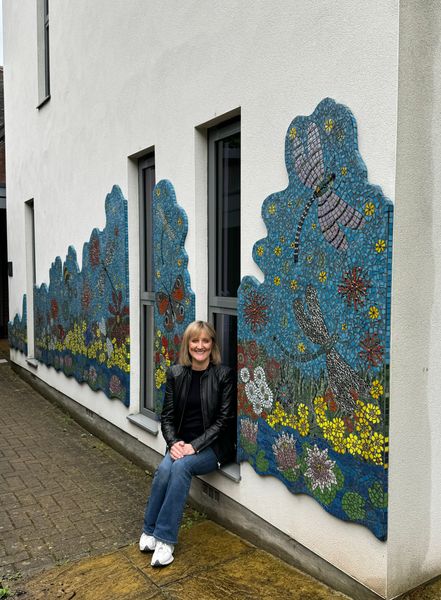 Jackie next to a mosaic she made for a hospice 