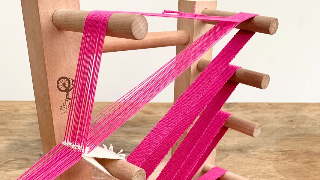 A band being woven on an inkle loom in organic cotton and linen