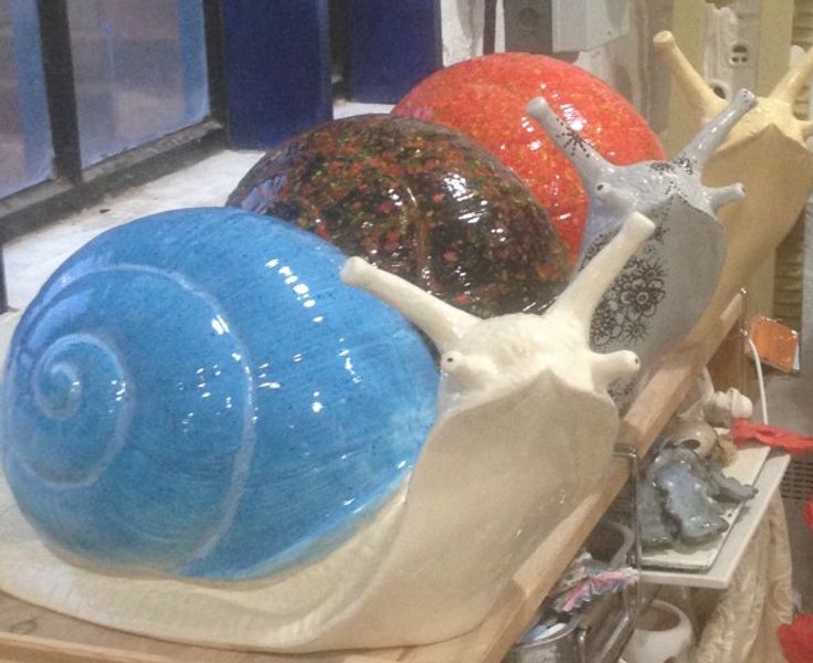 Three pottery giant snails painted by students on a glazing workshop in Wordsley