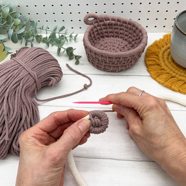 Hands stitching the rope into a coil