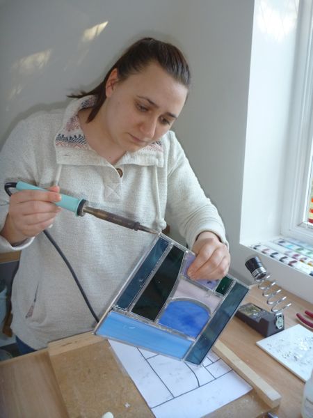 A customer soldering the corners of her first ever stained glass panel on a two day traditional leaded stained glass weekend in the Kent coutryside