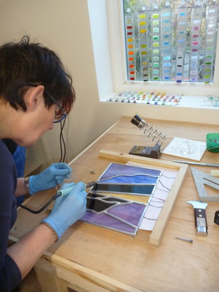 A beginner gets to grips with soldering her stained glass panel on a beginners' weekend stained glass course.