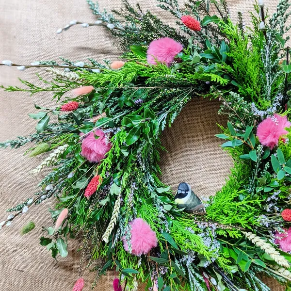 fresh foliage spring wreath with bird and pink pom poms