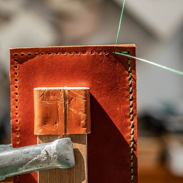 Saddle stitching a leather wallet in a lacing pony