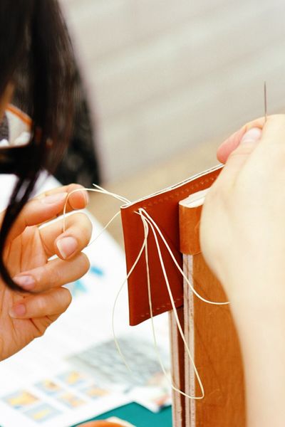 Student hand stitching a card holder
