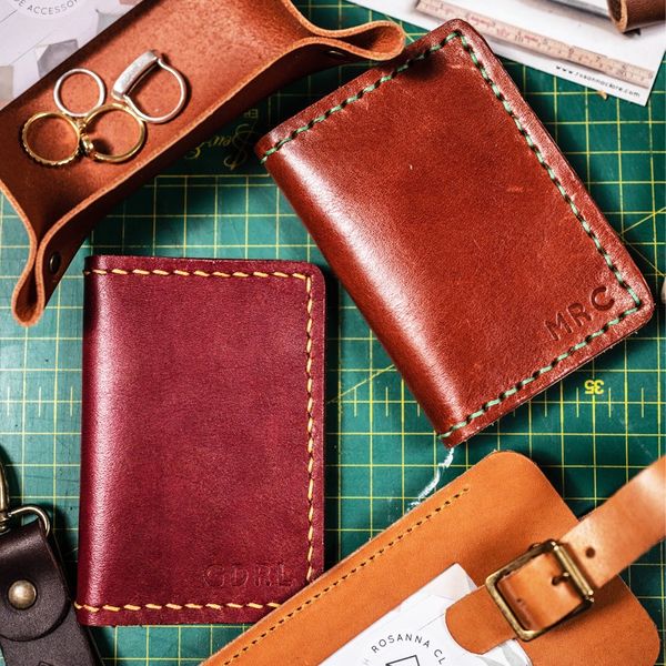 Hand stitched leather items including bifold wallets, luggage tag, a key fob and trinket tray