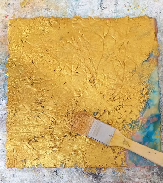 Over-painting a stencil with glorious ancient gold encaustic paint.