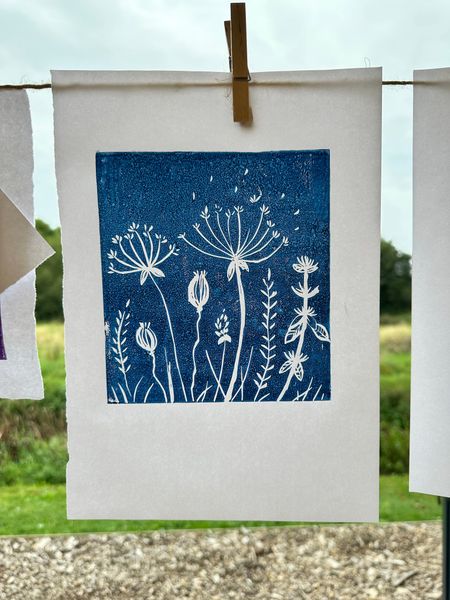 A blue lino print of seed heads and grasses