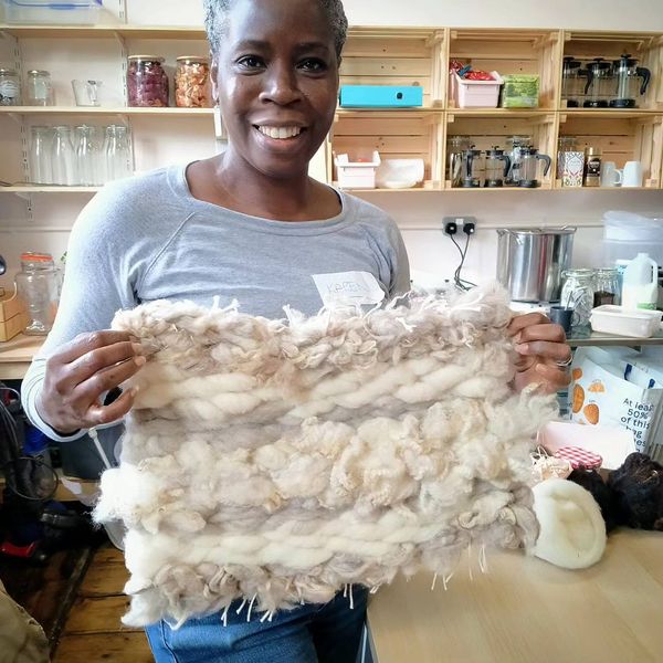 A woman smiling holding up her mat.