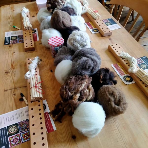 Peg looms and wool laid out on the table, ready for the workshop.