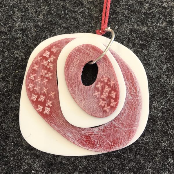 A student piece using stamps to embellish a pendant 