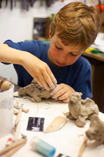 Child making imaginary animal in clay