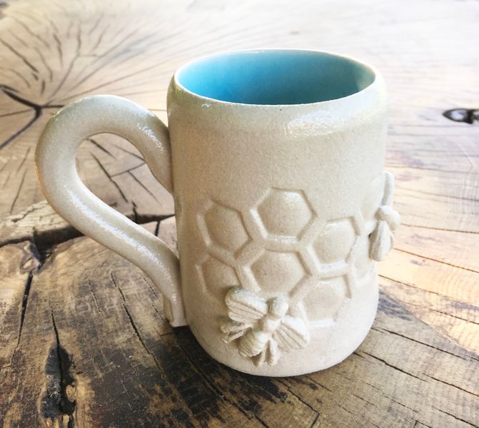 Mug made with a slab of clay, decorated with impressions for a beehive and bee sprigs