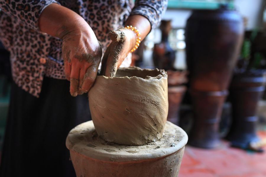 person moulding clay pot