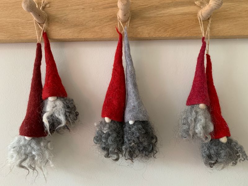 a row of Tomte hanging from a wooden coat rack