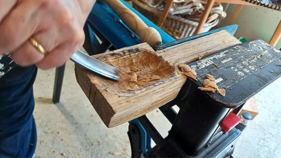 A crook knife being used to carve the indent in a spoon