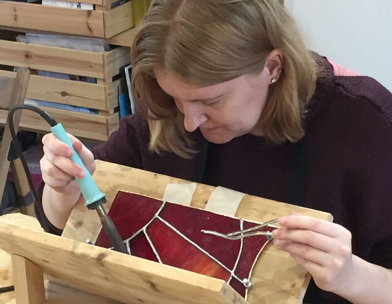 Rachel learning how to use a lamp jig to solder her lamp panels together