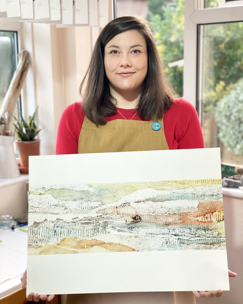 Tutor Hannah Cantellow holding a Collagraph landscape print in her studio