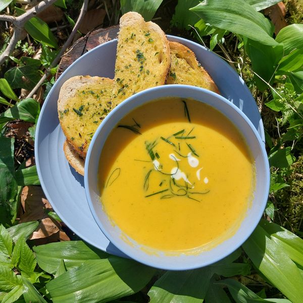 A bowl of delicious campfire cooked soup, with wild garlic bread.