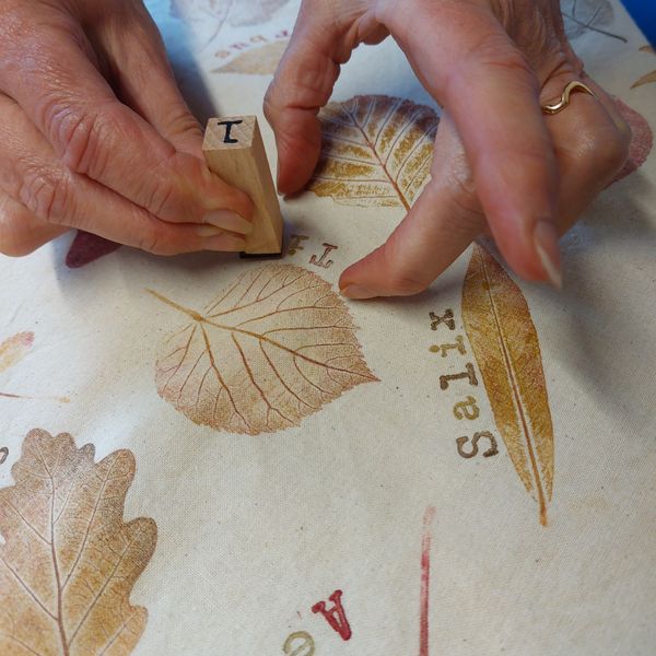 Adding the lettering to the tote bag using rubber stamps.