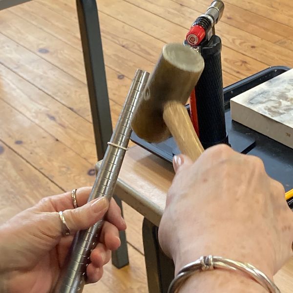 Creating the silver ring, making it round using a ring mandrel and hammer