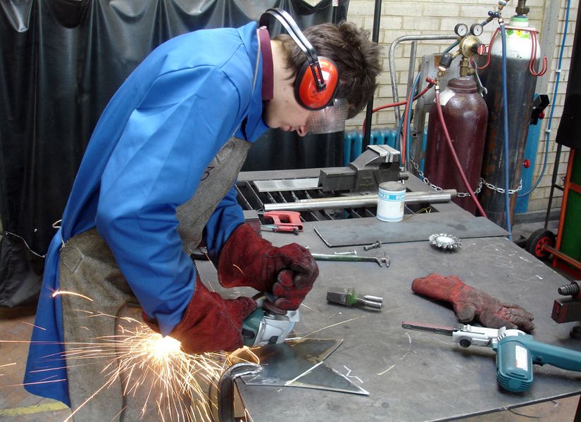 Student using an angle grinder to score lines in steel